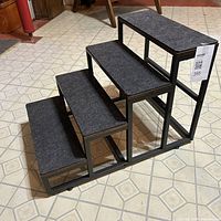 Side angle view showing four steps with fabric covering and metal frame structure, confirming stair type and condition.