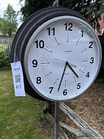 Close-up of the round clock face showing black numbers on white background with black metal casing.