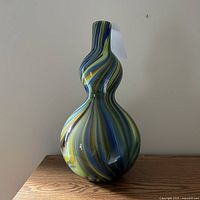 Full view of bulbous glass vase with blue, yellow, green swirled design showing shape and colors.