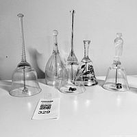 Front view showing all five glass hand bells with varied handles and designs on a white surface