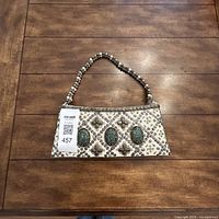 Front view of ivory Sitaraa clutch purse showing beadwork, three turquoise oval embellishments, pearl beaded handle, and zipper.