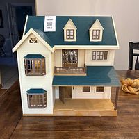 Front view of Sylvanian Families dollhouse with closed porch, green roof, beige walls, and multiple window features.