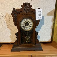 Full view of the antique wooden mantel clock showing carved details and clock face behind glass.