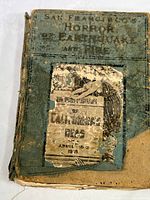 Front cover of antique book showing title 'San Francisco's Horror of Earthquake and Fire' with worn and partially torn paper label referencing California's 1906 earthquake.