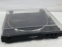 Audio-Technica AT-LP50XBT turntable with clear dust cover attached, showing front side and controls.
