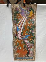 Full view of laminated painting showing two large colorful birds, rabbit, tree with purple flowers, on handmade paper with brown mottled border.