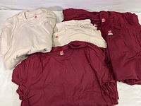 Pile of tan and maroon Hanes Nano-T t-shirts stacked showing color and quantity