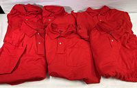 Folded red polo shirts stacked, showing collars and plackets with buttons.