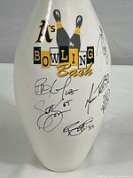 Front view of the white bowling pin showing Oakland Athletics Bowling Bash logo and multiple autographs in black ink.