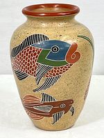 Front view of beige speckled ceramic vase with colorful fish patterns in red, green, blue, and black with reddish-brown rim.