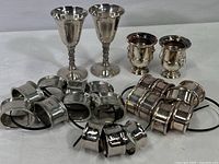 All silverplate items in grouping: two F.B. Rogers cordial stemware, two Department 56 urn motif votive holders, multiple silverplate napkin rings