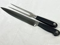 Pair of Usthof Grand Prix carving utensils including knife and fork with black handles and stainless blades.