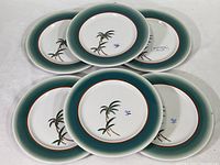Top view of six vintage Mayer China dinner plates arranged in a cluster, showing the palm tree design and green-orange rims.