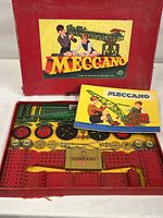 Original red box opened to show arranged metal parts and instruction manual on top.