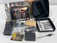 Overall contents of the lot including the radio, accessories, instructions, case, and batteries laid out next to the original box
