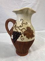 Front side view showing grape cluster and leaves with textured brown base and handle.