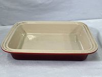 Top side view of the rectangular Le Creuset stoneware baking dish showing beige interior and signs of wear.