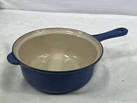 View of blue enamel cast iron sauce pan showing the interior and handle detail