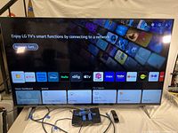 Smart TV powered on showing smart functions and app icons, connected to power and input cables.