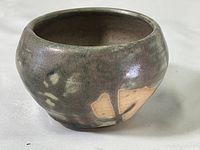 Side view of rounded multi-color glazed clay bowl showing abstract pattern and signature