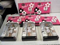 Three boxed See's Barbie dolls arranged in front of pink and black branded See's Barbie paper bags.