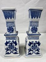 Pair of blue and white ceramic candle holders with chinoiserie floral patterns shown from the front.