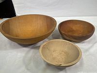 Overview of all three hand carved wooden bowls showing size range and color gradient from light to dark brown.