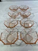 Eight pink glass octagonal candy dishes arranged on a white cloth background showing full set quantity and geometric pattern.