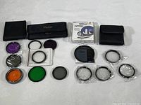 Set of multiple camera filters laid out with their storage pouches and plastic case to show variety and conditions.