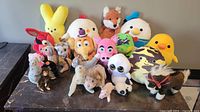 Front view of the 18 assorted plush toys displayed on a table, showing a variety of characters including Hello Kitty, owl, cow, and more.
