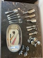 Full lot view on black marble surface, showing tray, forks, spoons, scoops, floral decorations.