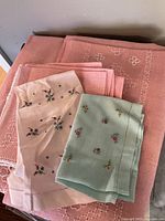 Pink embroidered tablecloth with matching napkins in pale pink and light teal, featuring small floral embroidery.
