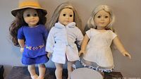 Three American Girl dolls with varied outfits displayed standing.