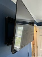 Side view of the black Insignia flat-screen TV mounted on a wall, showing thin bezels and reflective screen surface.