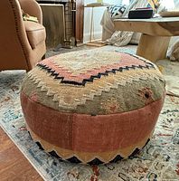 Photo showing the round woven fabric poof on a rug, capturing overall design and color.