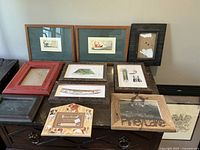 Overview of 9 rustic frames on a wooden dresser, some with art prints and one missing glass