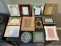 Overview photo showing 12 assorted picture frames arranged on a black surface, displaying variety in color, size and style.