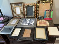 Full set of 13 picture frames on table showing various sizes, colors, and patterns including checkered, striped and floral accents.