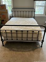 Full view of assembled vintage dark grey metal queen bed frame with headboard, footboard, mattress, and bedding.
