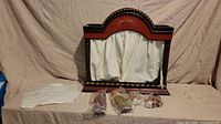 Wooden marionette stage with curtains and tie backs, four marionettes in original packaging laid out in front, and invoice document displayed.