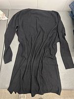 Black long-sleeve dress laid flat on a surface showing full body and sleeves.