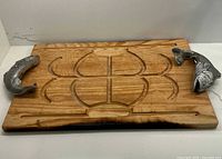 Rectangular wooden tray with carved compartments and metal fish handles visible from above