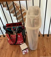 Overview of wrapping items showing plastic container with rolls, red tote with gift bags, and decorative gift box