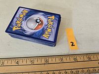 Stack of approximately 50 Pokémon cards shown from top, displaying the back design with a Poké Ball and Pokémon logo.