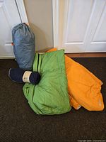 Tent packed in grey stuff sack, two sleeping bags, and navy blue fleece blanket