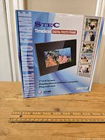 Front of sealed boxed Stec Timeless Digital Photo Frame, showing model DF073B, 7 inch LCD screen, features and product image.