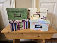 All four decorative photo boxes stacked and displayed on wooden table