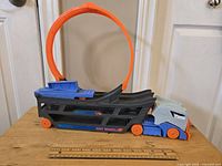 Side view of Hot Wheels stunt car track set with orange loop and grey and blue hauler truck.
