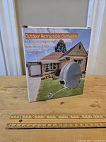 Front view of the boxed outdoor retractable clothesline showing product image and key features on packaging.
