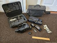 Full overview of camcorder lot with carrying bags, batteries, remote, cables, and accessories on floor
